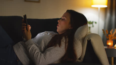 Primer-Plano-De-Una-Mujer-Tumbada-En-Un-Sofá-En-Casa-Viendo-Una-Película-O-Viendo-Una-Película-O-Navegando-Por-Internet-En-Un-Teléfono-Móvil-8